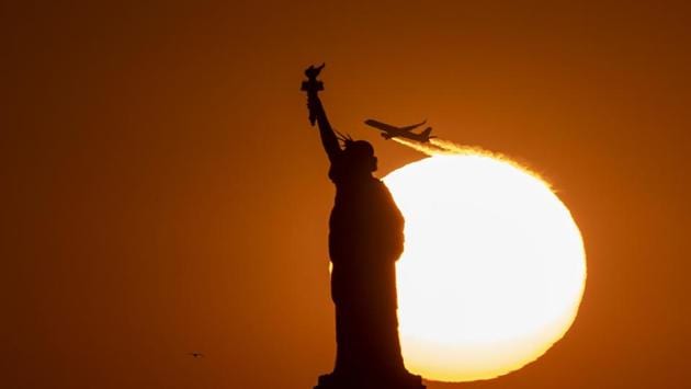 A plane flies behind the Statue of Liberty as the sun sets in New York City. (Johannes Eisele / AFP)