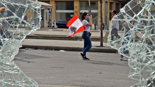 A masked woman walks with a Lebanese national flag tucked into her pocket past a broken window along a street in the centre of the capital Beirut amidst ongoing protests. Shattered by war between 1975 and 1990, Lebanon has one of the world’s highest debt burdens as a share of its economy. Economic growth has been hit by regional conflict and unemployment among the under-35s runs at 37%. (AFP)