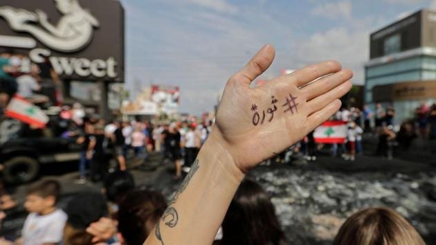 A Lebanese demonstrator displays the word “Revolution” in Arabic on the palm of their hand during a protest against dire economic conditions in Zouk Mikael, north of Beirut. Public anger has simmered since parliament passed an austerity budget in July to help trim a ballooning deficit and flared on Thursday over new plans to tax calls on messaging applications such as Whatsapp, forcing the government to axe the unpopular proposal. (Joseph Eid / AFP)