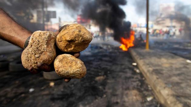 A woman walks by burning tires that were set fire to block a road during the protest. The demonstrations follow warnings by economists, investors and rating agencies that indebted Lebanon’s economy and graft-entrenched financial system are closer to the brink than at any time since the war-torn 1980s. (Ibrahim Amro / AFP)