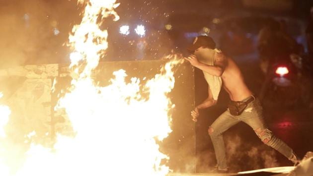 An anti-government protester sets fire to plastic barriers and trash to block a road during a demonstration in Beirut. Across the country, the protestors chanted for top leaders, including President Michel Aoun, Prime Minister Saad al-Hariri and Parliament Speaker Nabih Berri to step down. The mood was a mixture of rage, defiance and hope. (Hassan Ammar / AP)