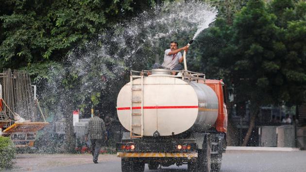 A man sprays water, mixed with an ecologically safe reagent, on a road to help precipitation of Suspended Particulate Matter (SPM) near the venue of Delhi half marathon in New Delhi. (Anushree Fadnavis / REUTERS)