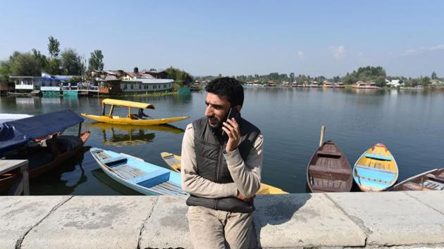 A man speaks on his mobile phone around the Dal Lake in Srinagar, Jammu and Kashmir. The government in Kashmir restored postpaid mobile services on October 14 after almost two and a half months. (Waseem Andrabi / HT Photo)