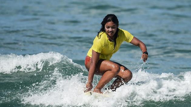 Nida Soe taking part in a surfing practice session. Paddling hard and smiling, she flung herself up on the board just as a wave was breaking, spreading her arms out for balance before getting knocked off. “I can’t live without surfing,” she said. (Ye Aung Thu / AFP)