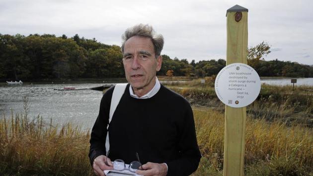 Artist Thomas Starr poses next to a sign, part of a public design installation, on the banks of the Oyster River in Durham. Starr, a graphic and information design professor from Boston's Northeastern University, created the project to address possible effects of climate change. (AP) Artist Thomas Starr poses next to a sign, part of a public design installation, on the banks of the Oyster River in Durham. Starr, a graphic and information design professor from Boston's Northeastern University, created the project to address possible effects of climate change. (AP)