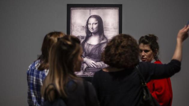 Journalists gather near a Mona Lisa image by Leonardo da Vinci during a visit at the Louvre museum Sunday, Oct. 20, 2019 in Paris. A unique group of artworks is displayed at the Louvre museum in addition to its collection of paintings and drawings by the Italian master. (AP)