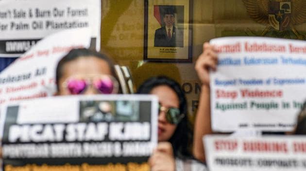 A portrait of Indonesian President Joko Widodo is seen past Indonesian migrant workers. Lestari’s network had planned to hold a rally in support of Indah on a Sunday, but they had to cancel it as it coincided with a local pro-democracy protest. They rescheduled to a weekday outside the Indonesian Consulate General calling for Jakarta to pressure Hong Kong to investigate, identify and prosecute the police officer. (Mohd Rasfan / AFP)
