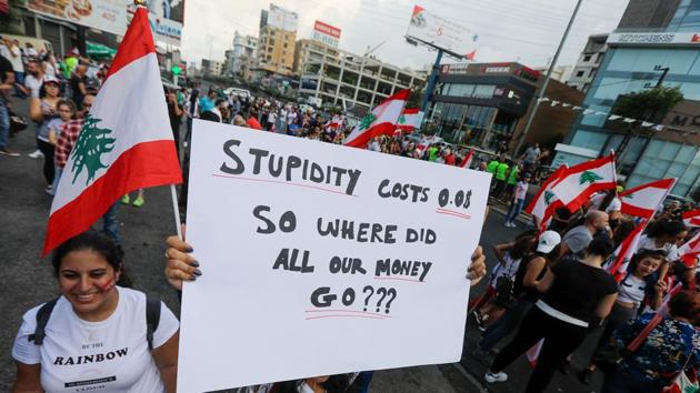 Lebanese demonstrators carry placards as they gather on a highway linking Beirut to north Lebanon, in Zouk Mosbeh on Sunday. Lebanon has one of the world’s highest levels of government debt as a share of economic output. The government includes most major parties, run by politicians widely perceived to have mobilised state resources and influence for their own gain. Unemployment among those under 35 runs at 37%. (Joseph Eid / AFP)