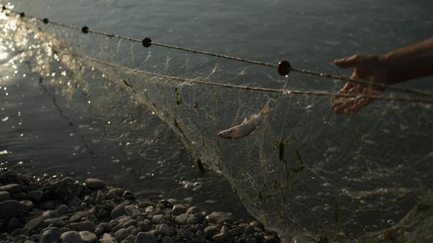Shyqyri Seiti, pulls his fishing net from the Vjosa River near Ane Vjose, Albania. The 65-year-old boatman has been transporting locals, goods and livestock across the river for about a quarter century. The construction of the proposed Kalivac dam would spell disaster for him. Many of the fields and some of the houses in his nearby village of Ane Vjose would be lost. (Felipe Dana / AP)
