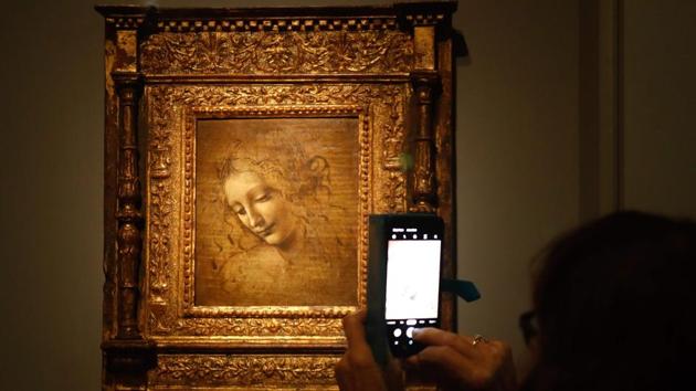 A person takes a picture of an oil on wood painting by Leonardo da Vinci’s “The Head of a Woman” — also known as La Scapigliata, during the show. That biographical emphasis is evident in the exhibit’s design, which traces the artist’s trajectory from his apprenticeship with Florentine sculptor Andrea del Verocchio to his death in France in 1519. (Francois Guillot / AFP) A person takes a picture of an oil on wood painting by Leonardo da Vinci’s “The Head of a Woman” — also known as La Scapigliata, during the show. That biographical emphasis is evident in the exhibit’s design, which traces the artist’s trajectory from his apprenticeship with Florentine sculptor Andrea del Verocchio to his death in France in 1519. (Francois Guillot / AFP)