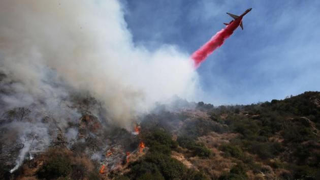 A firefighting aircraft drops the fire retardant Phos-Chek as firefighters watch during a wildfire threatening nearby hillside homes in the Pacific Palisades neighbourhood in Los Angeles, California. The fire scorched at least 40 acres and prompted mandatory evacuations. (Mario Tama / Getty Images / AFP)