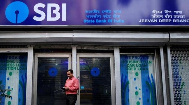 A man checks his mobile phone in front of State Bank of India (SBI) branch in Kolkata.(REUTERS)