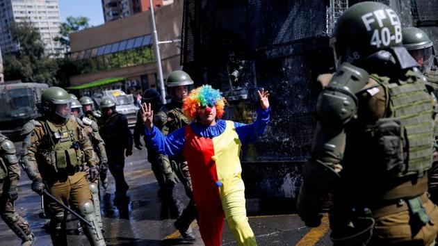 A demonstrator dressed as a clown gestures between police officers during a protest against Chile’s state economic model in Santiago, Chile. (Edgard Garrido / REUTERS)
