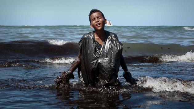 A boy walks out of the sea while removing oil spilled on Itapuama beach located in the city of Cabo de Santo Agostinho, Pernambuco state, Brazil. Large blobs of oil staining more than 130 beaches in northeastern Brazil began appearing in early September and have now turned up along a 2,000km stretch of the Atlantic coastline. The source of the patches remain a mystery. (Leo Malafaia / AFP)