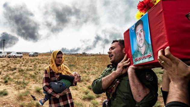 Mourners attend the funeral of civilians and fighters, who died during attacks by Turkish-led forces on the border town of Ras al-Ain, in a cemetary in Tal Tamr, near the Syrian Kurdish town of Ras al-Ain. Turkish and Kurdish leaders accused each other of violating a US-brokered truce in northeastern Syria even as it appeared to be taking hold. (Delil Souleiman / AFP)