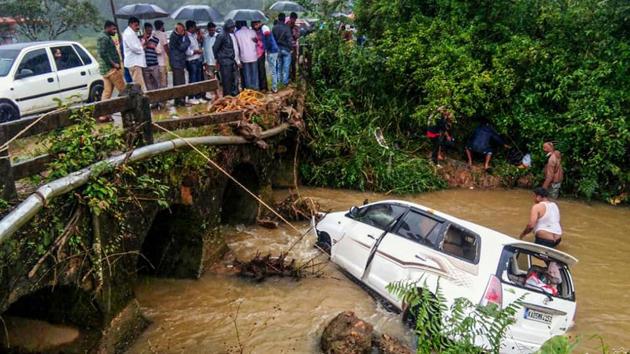 Onlookers watch after a car slid from a bridge to the stream following heavy rain near Chikmagalur in Karnataka. (PTI) Onlookers watch after a car slid from a bridge to the stream following heavy rain near Chikmagalur in Karnataka. (PTI)