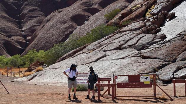 A ranger (R) briefs a tourist (L) at the base of Uluru after the permanent ban on climbing the monolith. As well as respecting cultural practices, the ban is designed to protect the site from further environmental damage and ensure visitors’ safety. “We are all very happy, as traditional owners, that the climb is closed now, after a long fight from handback to today,” Reggie Uluru told reporters through an interpreter on Saturday. (Saeed Khan / AFP)