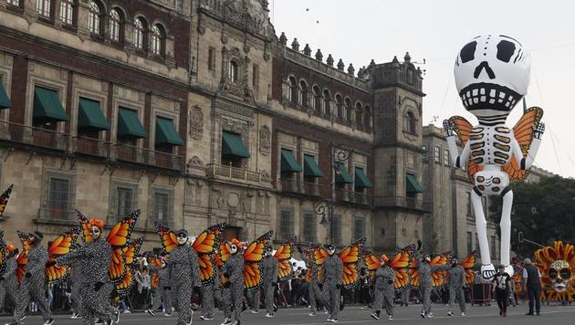 Performers in monarch butterfly costumes wave to the crowd as they walk in a Day of the Dead parade in Mexico City. (AP)