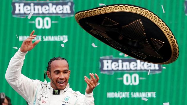 Mercedes' Lewis Hamilton celebrates winning the race on the podium throwing a sombrero(REUTERS)