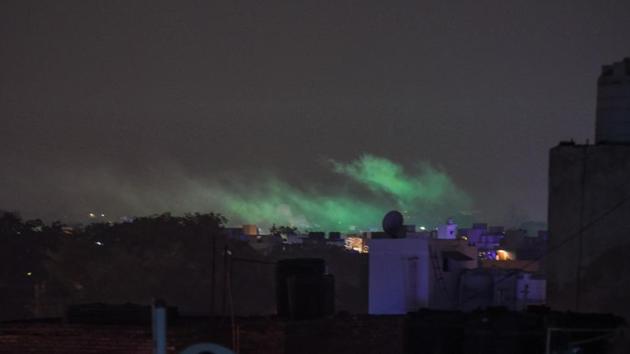 Residue from firecrackers wafts through the night sky on Sunday. People could also be seen bursting crackers before 8 PM, however, the intensity remained low. The levels of PM10 — tiny particulate matter of diameter 10 or less than 10 microns that can enter deep into the lungs — had on Sunday reached as high as 515 micrograms per cubic metre in Anand Vihar. (Amal KS / HT Photo)