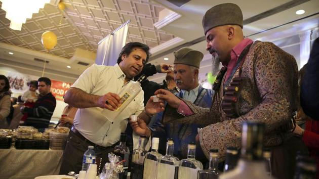 Bruce Khabbazi serves Arak Saggi to a man in a traditional Iranian "Qashqai" nomadic clothing, at the Arya Nowruz market in Toronto. His first product was pomegranate liquor. He now showcases three brands with the combined 40 products, which are available in the U.S., Canada, Europe and Australia. (Kamran Jebreili / AP)