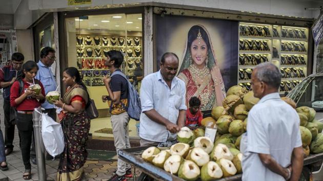 A street vendor cuts coconuts outside a jewellery store during the festival of Dhanteras in the Zaveri Bazaar in Mumbai, India, on Friday, October 25, 2019. Gold sales on the most auspicious day in India to buy the metal tumbled this year as high prices and concerns about an economic slowdown saw customers limit purchases. (Dhiraj Singh / Bloomberg)