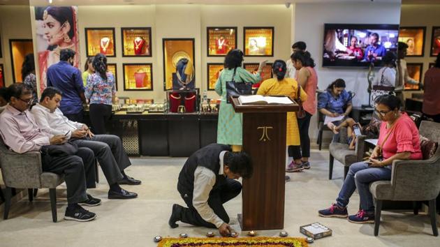 An employee lights candles around a flower rangoli inside a Titan Co. Tanishq jewellery store during the festival of Dhanteras which fell on Friday and came ahead of Diwali on Sunday. The day typically sees a pick up in demand as shoppers lock in gold purchases. This year though, there were shorter queues outside stores in Zaveri Bazaar, the country’s biggest bullion market. (Dhiraj Singh / Bloomberg)