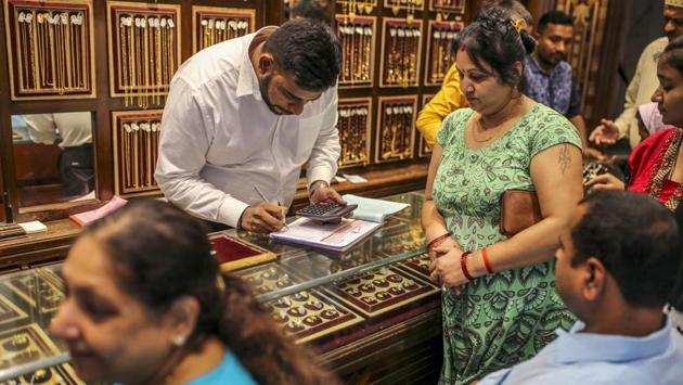 Customers browse gold jewellery as an employee writes on a counter. “I don’t have any special attraction toward gold, but since it is a tradition, we ensure that all our gold purchases of the year are made on the auspicious day of Dhanteras,” said 18-year-old Supriya Dixit, who was shopping with her mother. The two bought a ring for her sister’s engagement, combining a wedding purchase with Dhanteras. (Dhiraj Singh / Bloomberg)