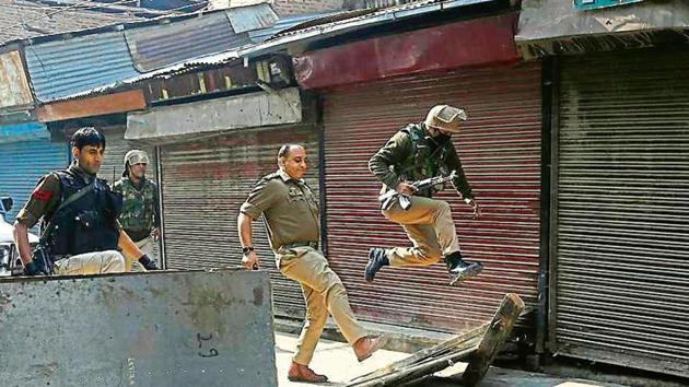 A policeman jumps as his officer kicks to remove a road block put up by protesters in Srinagar. (AP PHOTO) A policeman jumps as his officer kicks to remove a road block put up by protesters in Srinagar. (AP PHOTO)