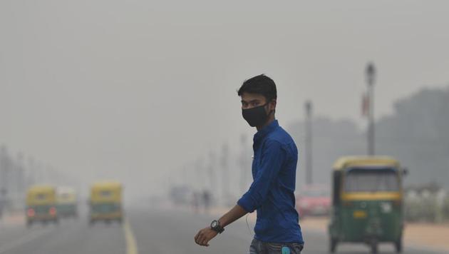 A man walks while wearing a pollution mask amid dense haze and low visibility as air quality in the national capital plunged to severe in many parts of the city.(HT photo/Burhaan Kinu)