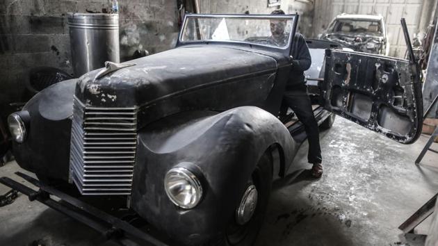 Munir Shindy at work. Hossam Ayoub, a neighbour, came to stare at the car. “It’s amazing. Vintage cars like this are part of history,” he said. “No one knows this kind of car here. It’s something unusual.” (Mahmud Hams / AFP)