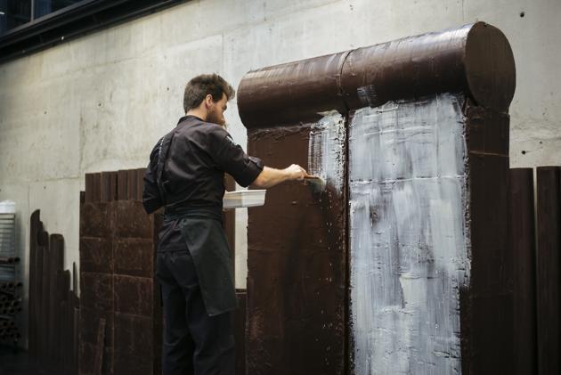 French chocolate maker Patrick Roger's creative assistant Angelo Dao adds white chocolate to a dark chocolate reproduction of the Berlin wall, in Sceaux, outside Paris, Wednesday, Oct. 30, 2019 to mark the upcoming 30th anniversary of the fall of the Berlin Wall. (AP Photo/Kamil Zihnioglu) (AP)