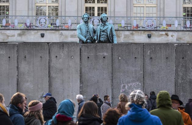 A wall, an art performance of the National Theatre Weimar, stand in front of the memorial of German poets Johann Wolfgang von Goethe, left, and Friedrich Schiller, right, prior the 30th anniversary of falling Berlin wall in Weimar, Germany, Wednesday, Oct. 30, 2019. With the temporary installation of 17 wall elements, the National Theatre recall the events of autumn 1989. The artist Christina Wildgrube designs this 'wall'. Unlike the former Belin wall, the art project should not create a long-term separation, but bring people together. (AP Photo/Jens Meyer) (AP)
