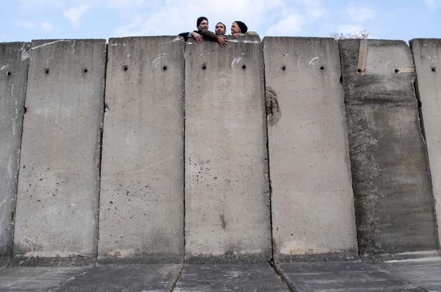 Artists look over the wall during the art performance 'Wall watching - climb the wall together' of the National Theatre Weimar prior the 30th anniversary of falling Berlin wall in Weimar, Germany, Wednesday, Oct. 30, 2019. With the temporary installation of 17 wall elements, the National Theatre recall the events of autumn 1989. The artist Christina Wildgrube designs this 'wall'. Unlike the former Belin wall, the art project should not create a long-term separation, but bring people together. (AP Photo/Jens Meyer) (AP)