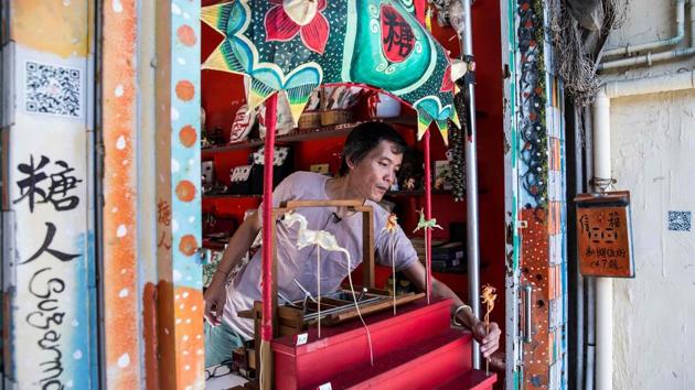Louis To puts a figurine-shaped piece of candy on display for sale at his shop on Cheung Chau Island in Hong Kong. Using a pair of scissors, a blow pipe and small metal tools, Hong Kong shopkeeper Louis To whittles chunks of molten sugar into intricate designs such as dragons --a talent he began honing during China’s Cultural Revolution. (Isaac Lawrence / AFP) Louis To puts a figurine-shaped piece of candy on display for sale at his shop on Cheung Chau Island in Hong Kong. Using a pair of scissors, a blow pipe and small metal tools, Hong Kong shopkeeper Louis To whittles chunks of molten sugar into intricate designs such as dragons --a talent he began honing during China’s Cultural Revolution. (Isaac Lawrence / AFP)