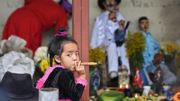 A three-year-old girl smokes a cigar during the Saint Simon celebrations in San Andres Itzapa, Guatemala. Popular belief holds that the saint helps people find work, solves family problems and cures illnesses. (Orlando Estrada / AFP) A three-year-old girl smokes a cigar during the Saint Simon celebrations in San Andres Itzapa, Guatemala. Popular belief holds that the saint helps people find work, solves family problems and cures illnesses. (Orlando Estrada / AFP)