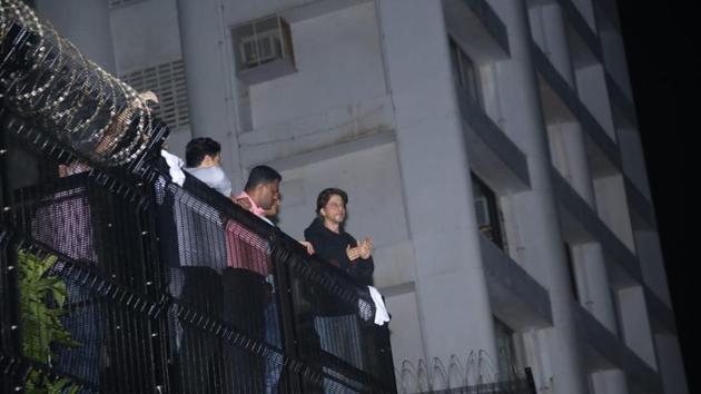 Shah Rukh Khan greets his fans from the balcony of his home.