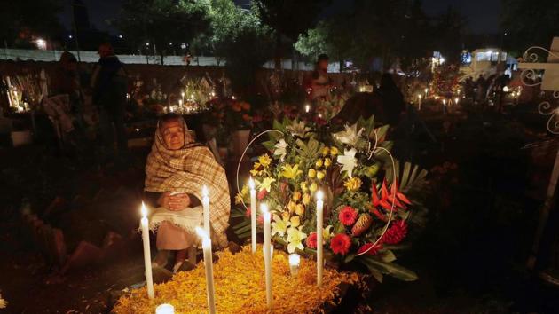 A relative spends the night next to a child's tomb in the San Gregorio Atlapulco cemetery during Day of the Dead festivities on the outskirts of Mexico City.  (AP) 