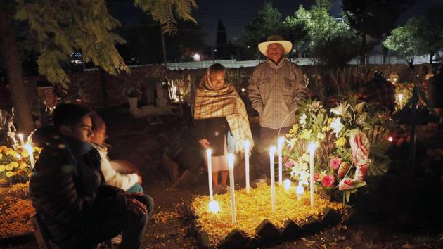 Relatives spend the night next to the tomb of tier loved one in the San Gregorio Atlapulco cemetery. (AP) 