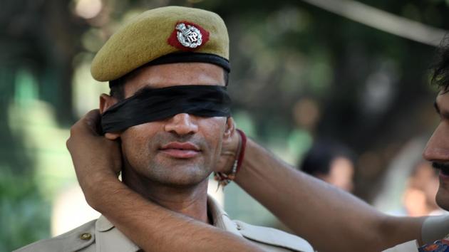 A Delhi Police personnel is seen blindfolded during a protest outside the Delhi Police headquarters, at ITO, in New Delhi. Thousands of police personnel protested outside the Delhi Police headquarters on Tuesday in an unprecedented public demonstration of anger over an assault on members of the force by lawyers after a violent clash on the weekend, and to express their resentment at senior officers for not rising to their support. (Raj K Raj / HT Photo)