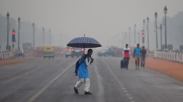 A girl walks with an umbrella as it rains rains, at Rajpath, in New Delhi. The wind direction on Wednesday was south-easterly, not carrying pollution from Punjab and Haryana to the northwest where crop stubble burning is underway. There were however more than 4,000 crop stubble fires in Punjab and Haryana on Wednesday as per NASA data. (Amal KS / HT Photo)