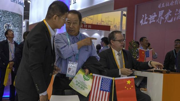 In this photo taken Wednesday, Nov. 6, 2019, visitors chat near American and Chinese flags displayed at a booth of an American company promoting environmental sensors during the China International Import Expo in Shanghai. Washington and Beijing have agreed to cancel tariff hikes as their trade negotiations progress, a Chinese Commerce Ministry spokesman said Thursday, Nov. 7, 2019. (AP) In this photo taken Wednesday, Nov. 6, 2019, visitors chat near American and Chinese flags displayed at a booth of an American company promoting environmental sensors during the China International Import Expo in Shanghai. Washington and Beijing have agreed to cancel tariff hikes as their trade negotiations progress, a Chinese Commerce Ministry spokesman said Thursday, Nov. 7, 2019. (AP)