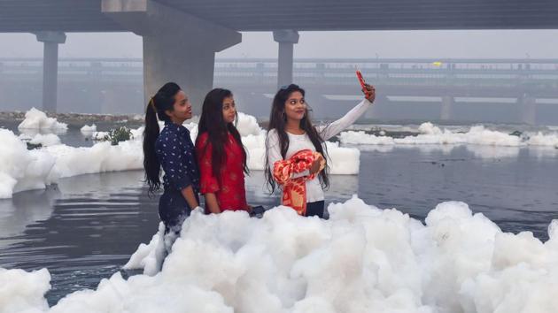 Women pose for a selfie as toxic foam floats on the surface of the polluted river. There are no fishes in the Yamuna due to lack of oxygen. Yamuna fulfills three-quarters of the capital’s water needs. Several polluting industrial units pollute the water of the river on a daily basis, regardless of the fact. (Manvender Vashist / PTI)