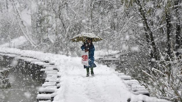 A girl walks on a snow covered foot bridge during the first snowfall of the season in the interiors of Dal Lake, Srinagar, Jammu and Kashmir, India (Photo by Waseem Andrabi / Hindustan Times)