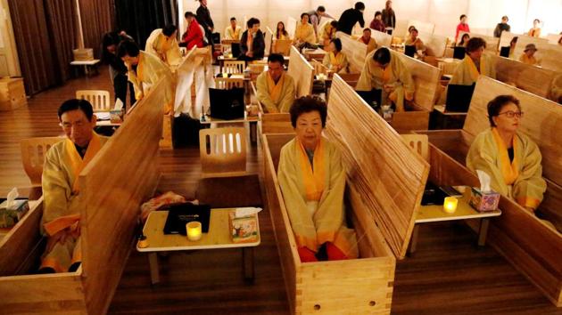 Participants sit inside coffins during a “living funeral” event as part of a “dying well” programme, in Seoul, South Korea. (Heo Ran / REUTERS)