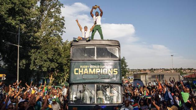 South African Rugby captain Siya Kolisi (C) holds up the Web Ellis trophy as the World Cup winner team parades Vilakazi street in Soweto on an open top bus in Soweto, South Africa. (Michele Spatari / AFP)