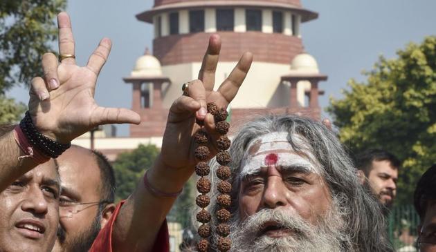 New Delhi: A sadhu flashes the victory sign at the Supreme Court complex after the pronouncement of the Ayodhya case verdict, in New Delhi, Saturday, Nov. 9, 2019. (PTI Photo/Manvender Vashist) (PTI11_9_2019_000067B)(PTI)