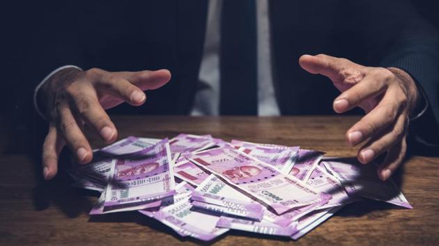 Businessman taking pile of money, Indian Rupee banknotes, on his desk in a dark office - corruption concept (Getty Images/iStockphoto) Businessman taking pile of money, Indian Rupee banknotes, on his desk in a dark office - corruption concept (Getty Images/iStockphoto)