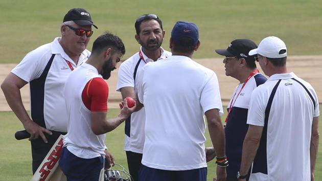 India's captain Virat Kohli, second left, checks out the new pink ball as he interacts with umpires.(AP)