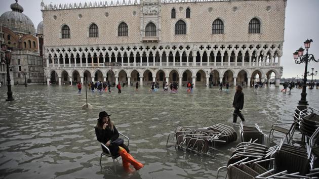 A woman sits in a chair in a flooded St. Mark's Square, in Venice on November 13, 2019. St Mark’s Square was calm on Wednesday evening, with just a smattering of tourists walking through the relatively dry square marked with occasional puddles. (Luca Bruno / AP) A woman sits in a chair in a flooded St. Mark's Square, in Venice on November 13, 2019. St Mark’s Square was calm on Wednesday evening, with just a smattering of tourists walking through the relatively dry square marked with occasional puddles. (Luca Bruno / AP)